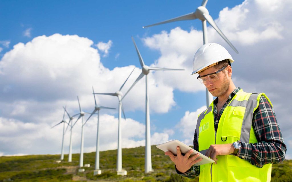Engineer in a high-visibility vest and hard hat using a tablet.
