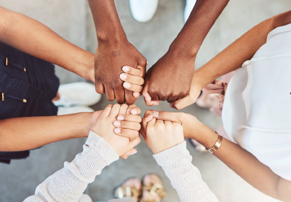 Group of diverse hands joining together in a circle.