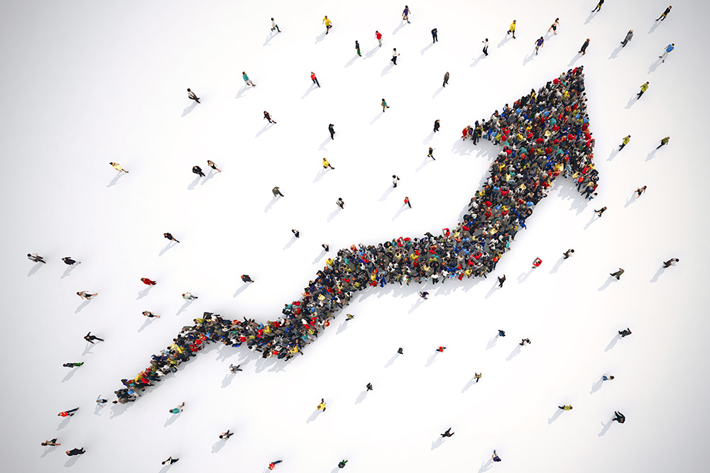 A large group of people arranged to form an upward-pointing arrow, symbolizing growth and progress, viewed from above.