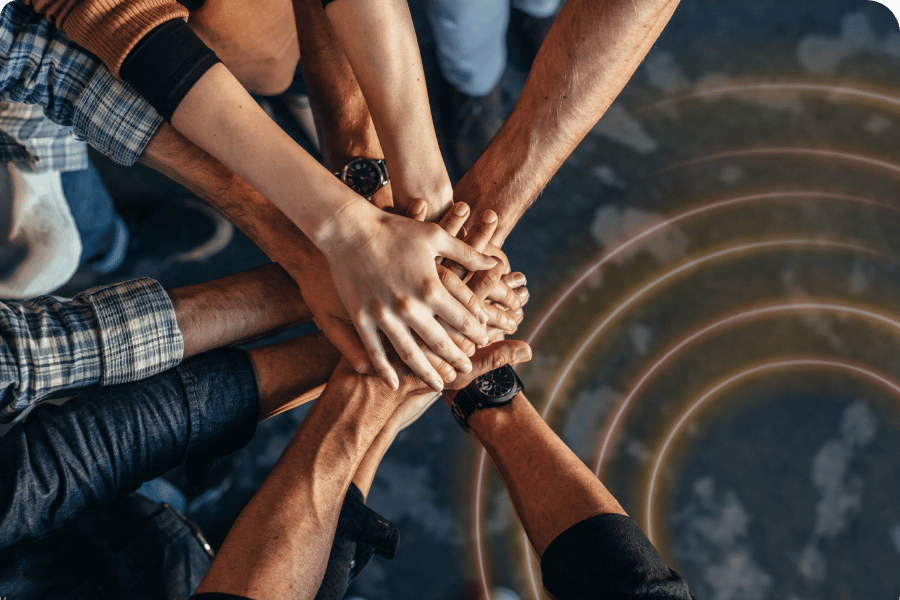 Team putting their hands together in a unified stack, symbolizing collaboration and alignment during a Data 360 initiative.
