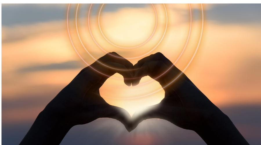 Two hands in the sunset forming a heart shape