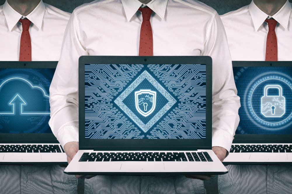 Three cybersecurity professionals collaborating on secure cloud technology using laptops